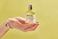 A person holds up a bottle of Le Labo Santal 33 Eau de Parfum