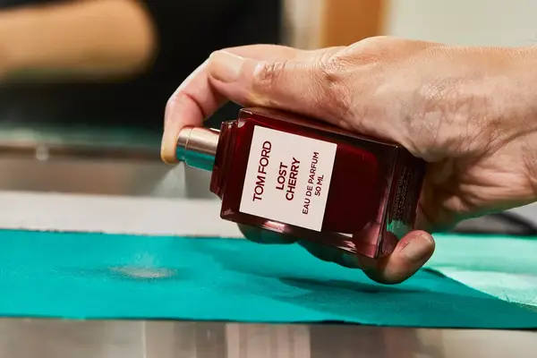 A person sprays Tom Ford Lost Cherry Eau de Parfum onto fabric