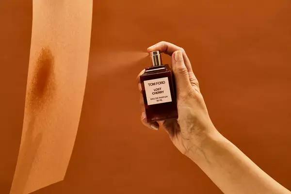 A person sprays Tom Ford Lost Cherry Eau de Parfum onto a piece of paper