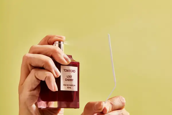 A person sprays a paper test strip with Tom Ford Lost Cherry Eau de Parfum
