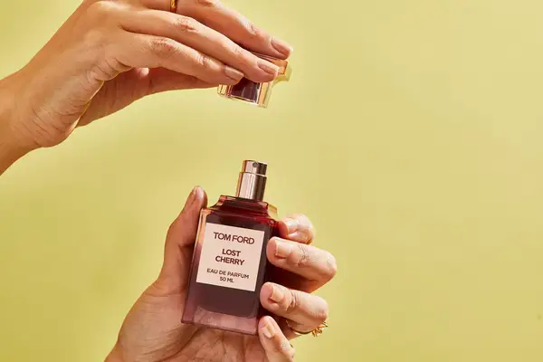 A person removes the cap on a bottle of Tom Ford Lost Cherry Eau de Parfum