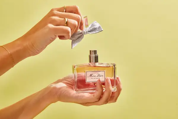 A person removes the cap from a bottle of DIOR Miss Dior Eau de Parfum