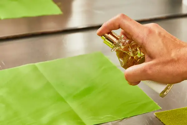 A person sprays Creed Aventus for Her onto fabric