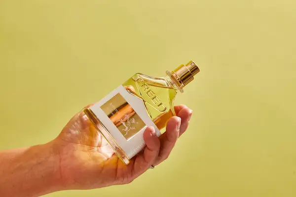 A person holds up a bottle of Creed Aventus for Her