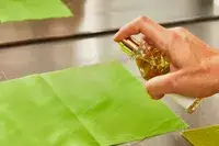 A person sprays Creed Aventus for Her onto fabric