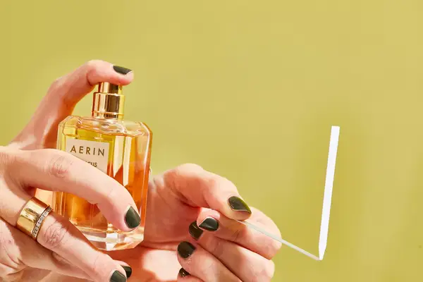 A person sprays AERIN Hibiscus Palm Eau de Parfum onto a paper test strip
