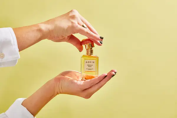 A person removes the cap on the AERIN Hibiscus Palm Eau de Parfum