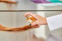 A person sprays AERIN Hibiscus Palm Eau de Parfum onto hair