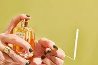 A person sprays AERIN Hibiscus Palm Eau de Parfum onto a paper test strip