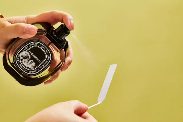 A person sprays Diptyque Philosykos onto a paper test strip