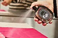 A person sprays Diptyque Philosykos onto fabric