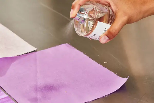 A person sprays Byredo Mojave Ghost onto fabric