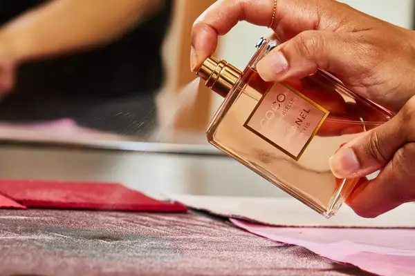 A person sprays fabric with Chanel Coco Mademoiselle perfume