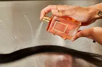 A person sprays hair with Chanel Coco Mademoiselle perfume