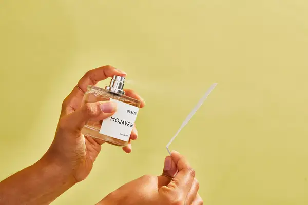 A person sprays a paper test strip with Byredo Mojave Ghost