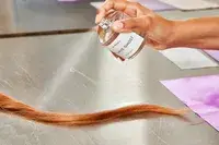 A person sprays Byredo Mojave Ghost onto hair