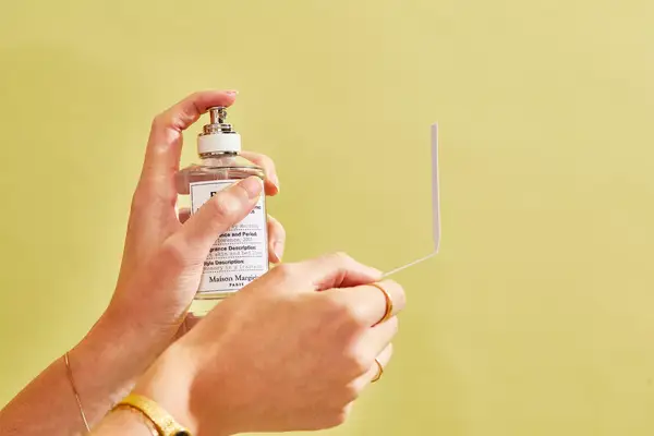 A person sprays a paper test strip with Maison Margiela Replica Lazy Sunday Morning Perfume