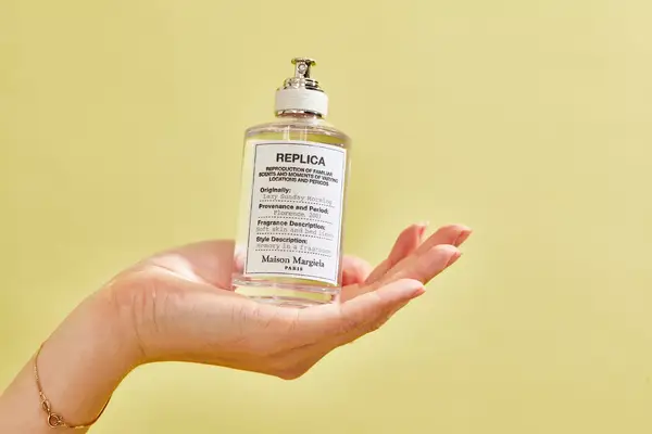 A person holds up a bottle of Maison Margiela Replica Lazy Sunday Morning Perfume