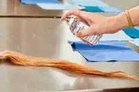 A person sprays hair with Maison Margiela Replica Lazy Sunday Morning Perfume