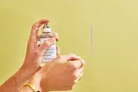 A person sprays a paper test strip with Maison Margiela Replica Lazy Sunday Morning Perfume