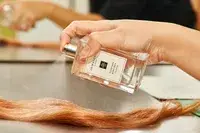 A person sprays Jo Malone Wood Sage and Sea Salt onto hair