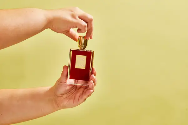 A person removes the top on a bottle of Killian Paris Rolling In Love