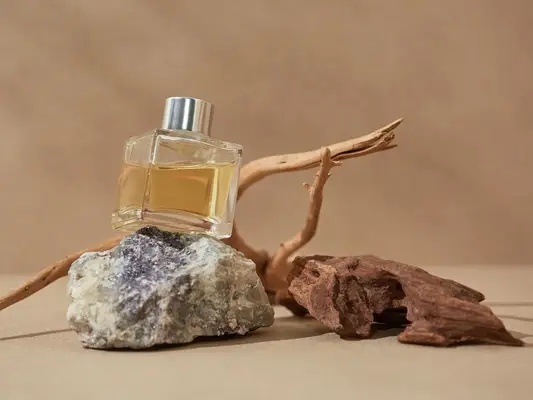 Bottle of perfume oil with rock, stick, and piece of wood