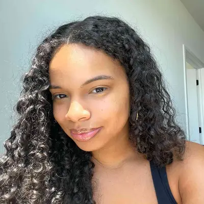 MYM Beauty editor Olivia Hancock poses with fresh, radiant skin, defined curls, and glossy lips