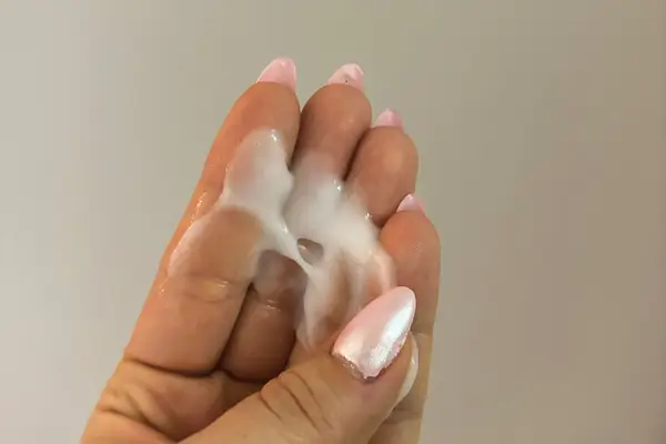 A person shows the color and texture of Ouidad Moisture Lock Leave-In Conditioner