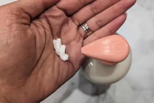 A person holds Melanin Haircare Multi-Use Softening Leave In Conditioner in the palm of their hand