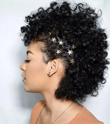 Side view of curly faux hawk hairstyle with star adornments