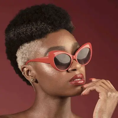 Woman with naturally curly mohawk with bleached sides and red sunglasses
