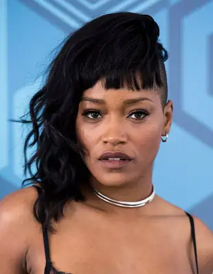 Keke Palmer with a long asymmetrical haircut with bangs and shaved sides