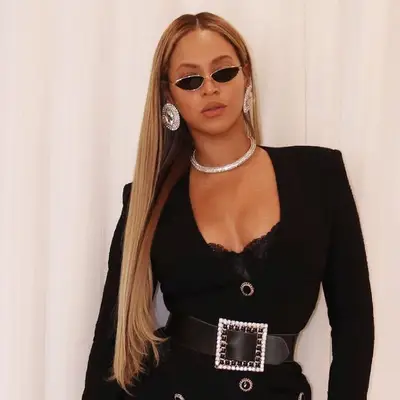 Beyonce wears a long, sleek blonde blowout with center part and tiny sunglasses