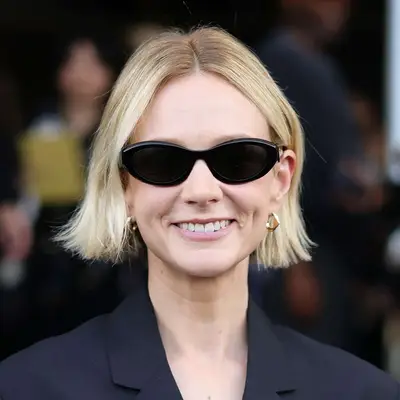 Carey Mulligan wears a cool casual flipped out bob with sunglasses and a pantsuit