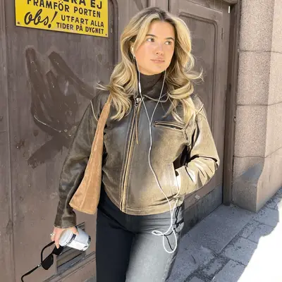 Matilda Djerf wearing a brown leather jacket and white headphones.