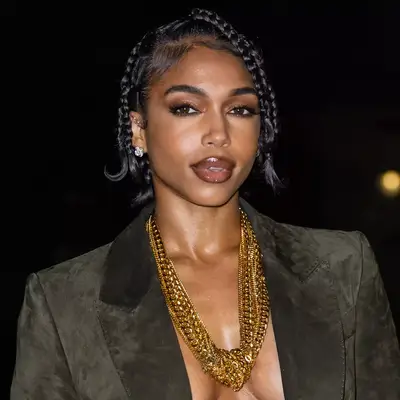 Kelly Rowland smiling in one shoulder green top and side part blonde bob with swoop