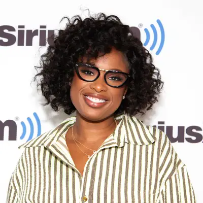 Jennifer Hudson smiling with black glasses and wand curled side part afro