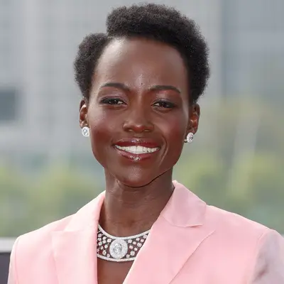 Rihanna looking over her shoulder with soft glam makeup and blonde curly mini afro