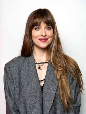 Dakota Johnson in West Hollywood with blunt bangs and long, highlighted hair over a gray coat