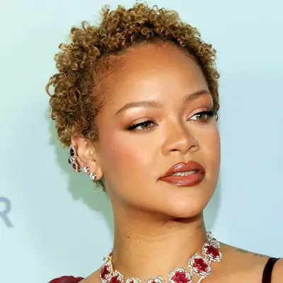Rihanna wears natural hair texture in a golden blonde buzz cut to a Fenty event