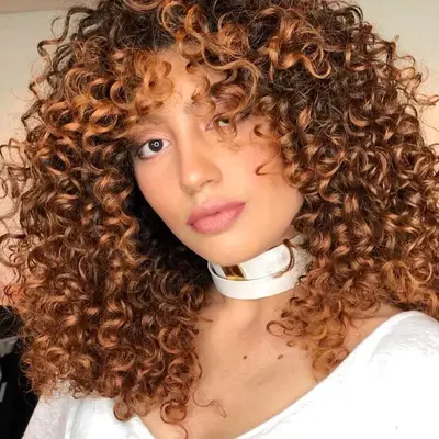 Person with curly caramel highlights 