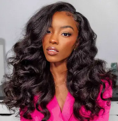 woman with loose waves and side part wearing pink blazer