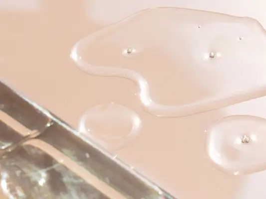 Close up of drops of mineral oil on a pink background