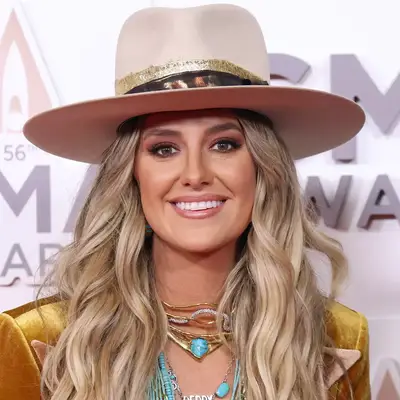 Lainey Wilson attends the CMAs wearing simple long waves and a large Stetson hat