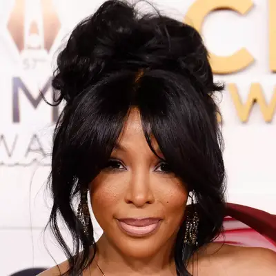 K. Michelle wears volumptuous curtain bangs and a large top knot to the CMAs