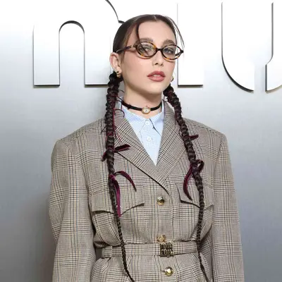 Emma Chamberlain with two long braids and ribbons all over at the Miu Miu Spring/Summer 2024 runway show in Paris, France