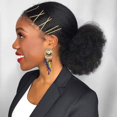 A girl with a puffy low bun and big gold bobby pins