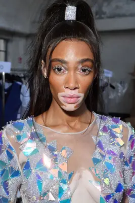 Winnie Harlow in a sleek half-up, half-down hairdo with sparkly rhinestone cuff