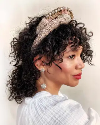 A woman with voluminous curly hair and two headbands 